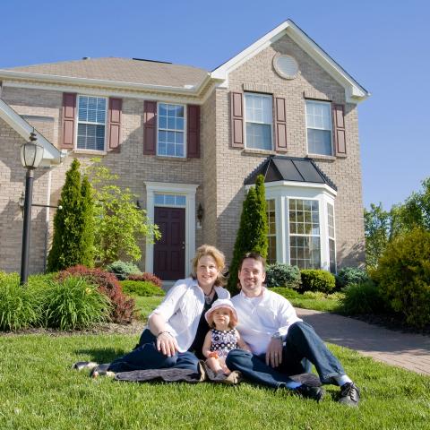 A Family Sits in Front of Their Home.