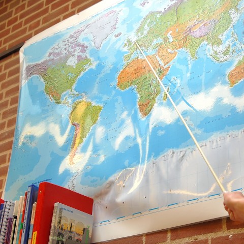 A Hand Pointing with a Stick at a World Map