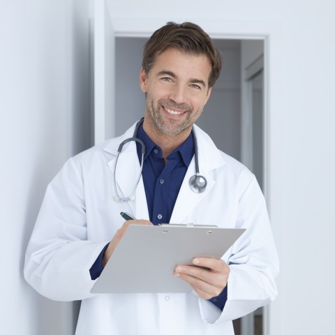 A Doctor Smiling and Holding a Clipboard