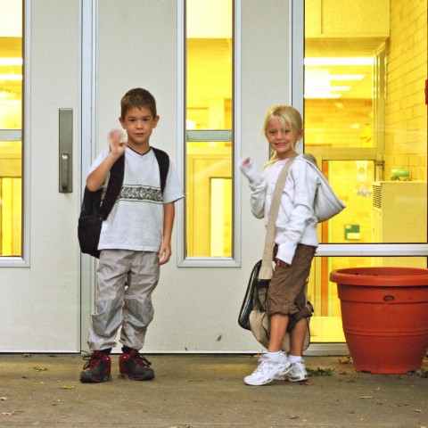 Two Children Waving Goodbye to Their Friends After School