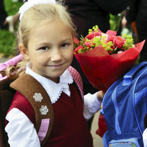 A Little Girl with a Backpack and Flower Bouquet Heading to School 