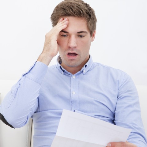 A Man Looking Surprised at a Paper He’s Reading