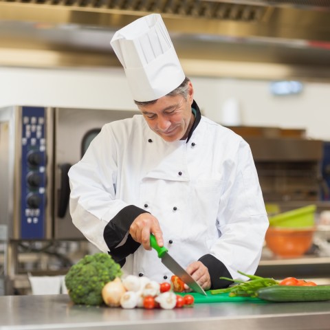 A Smiling Chef Preparing a Vegetable Dish.
