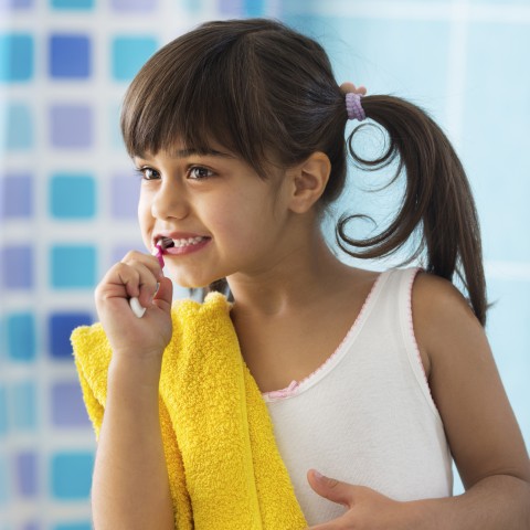 A Young Child Brushing Her Teeth in the Bathroom
