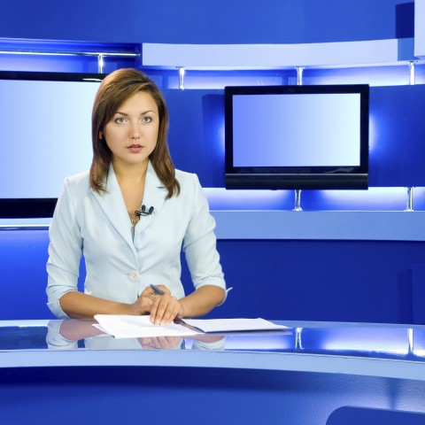 A Female Newscaster Sitting in a Studio