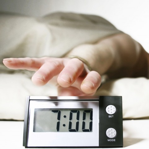 Man in Bed Reaching for an Alarm Clock