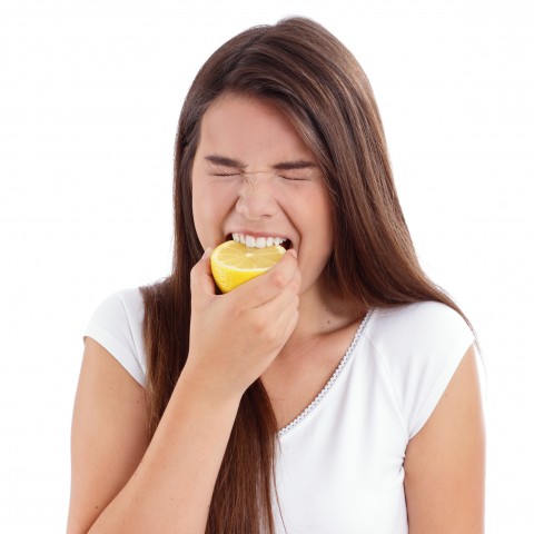 A Woman Biting a Sour Lemon