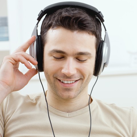 A Guy Smiling and Listening to Something with Headphones On 