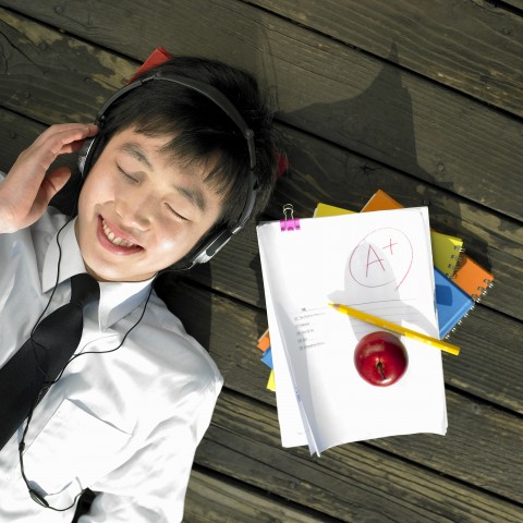 A Smiling Student with Headphones Lying next to a Paper Graded A+