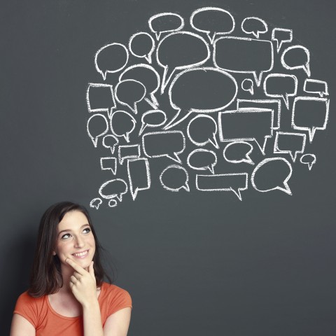 A Woman Thinking in Front of a Blackboard with Thought Bubbles Drawn in Chalk