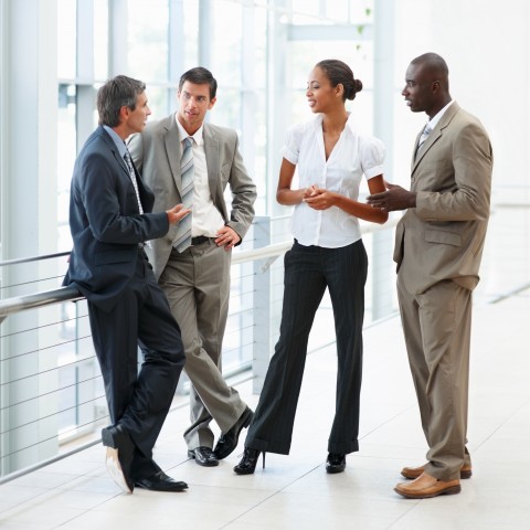 Group of Four in Business Gear Chatting in an Office Setting