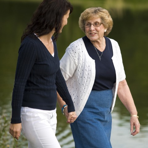 A Woman Holding Hands and Walking with an Older Woman