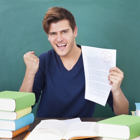 A Triumphant Male Student Holding Up an A-graded Paper.