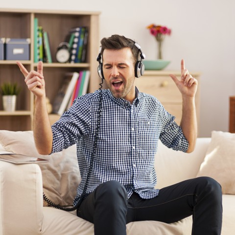 Guy listening to music with headphones on, singing along and enjoying himself