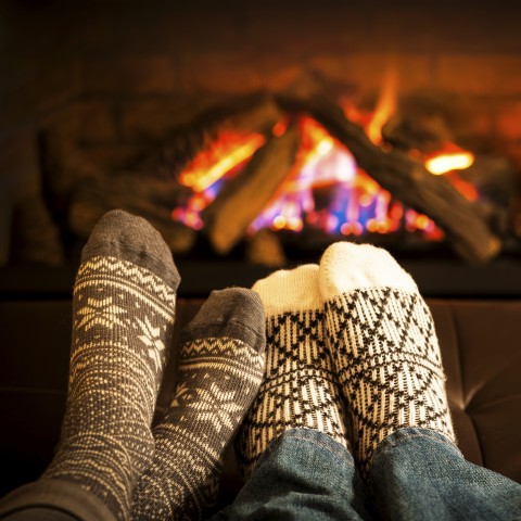 People with Christmas socks getting warm in front of a fire