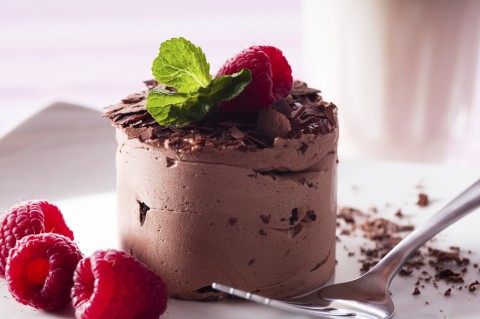 A Gourmet Chocolate Dessert with Raspberries and Green Garnish.