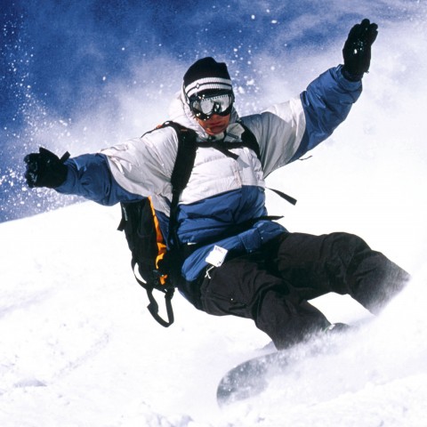 Мужчина катается на сноуборде с горы