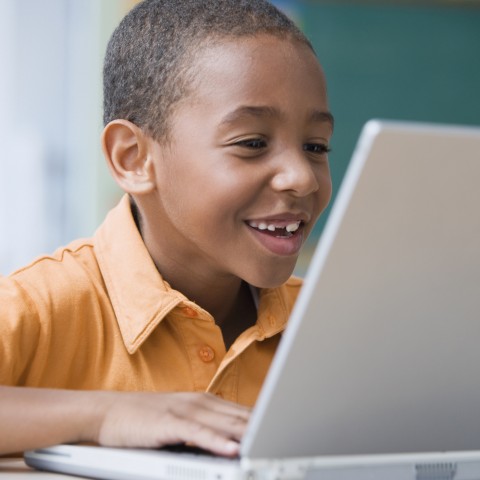 A Boy Smiling while Using a Laptop