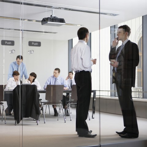 A Group of People in Business Gear, Sitting and Standing in the Glass Office