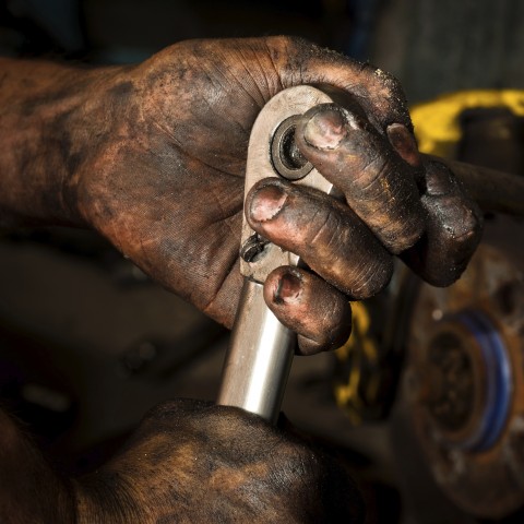 Greasy Mechanic's Hand Holding a Tool