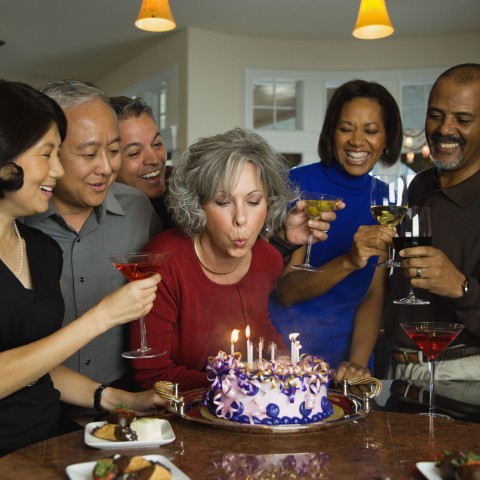 Older Woman Blowing Out Birthday Cake Candles