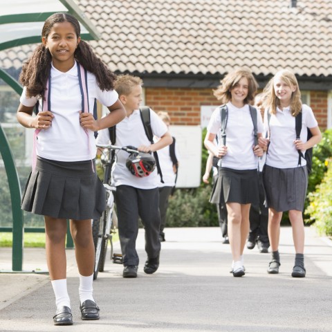 School Children in Uniform Walking with Their Backpacks at School.