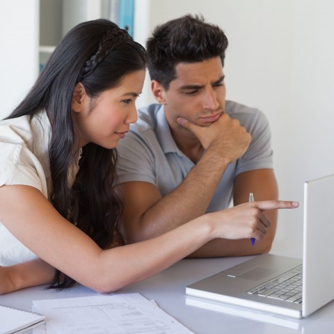 One Asian and One Black-haired Man Discussing Something Shown on a Laptop