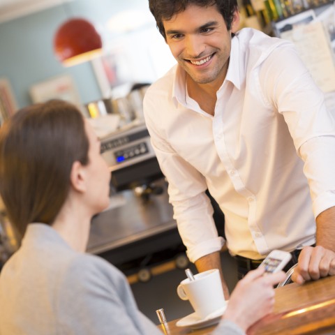 A Man Smiling at a Woman at a Coffee Shop