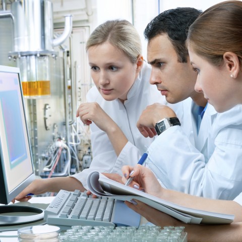 three researchers examining and recording data