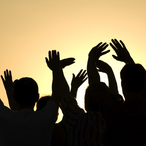 Silhouettes of People Waving Their Hands in the Air