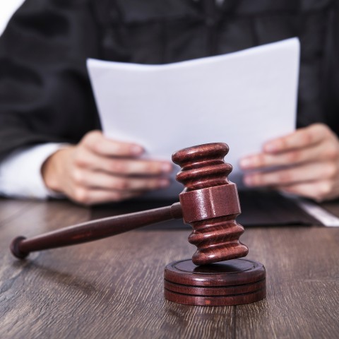 Close-up of a Gavel on a Desk, with a Judge Sitting in the Background