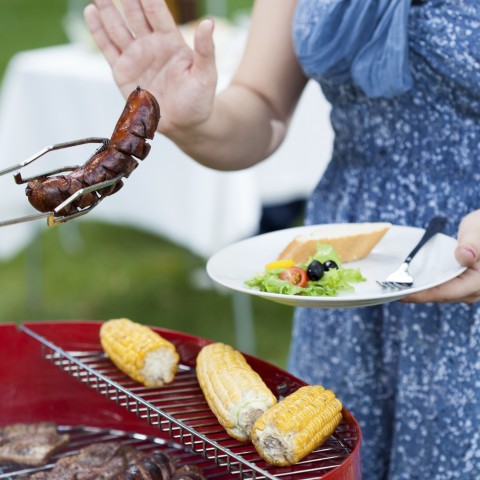 A Woman Holding a Plate and Refusing a Sausage 