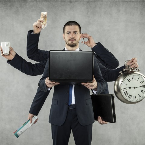 Multitasking Businessman Holding Clock, Laptop, Briefcase, etc.