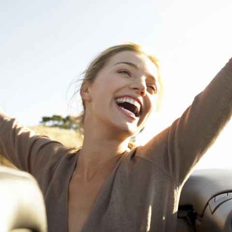 A Woman Raising Her Arms above Her Head and Smiling