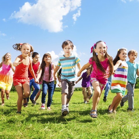 A Group of Children Running on Grass.