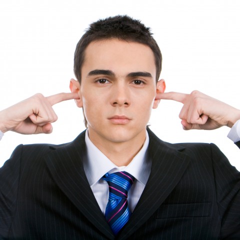 A Man in a Suit Plugging His Ears with His Fingers