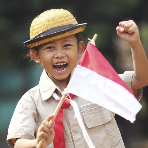 An Indonesian Child Waving a Small Indonesian Flag