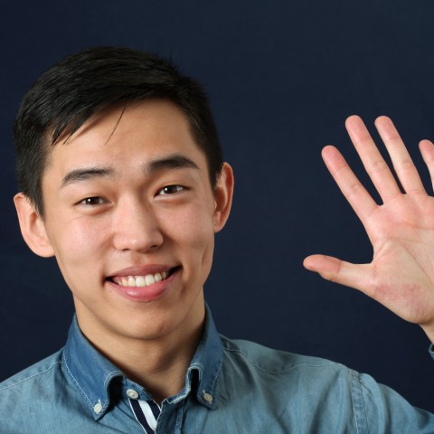 An Asian Man Waving to Someone and Smiling