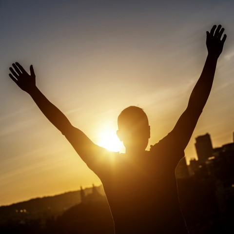 A Silhouette of Someone Raising Their Hands in Victory Toward the Sunset