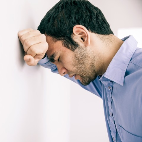 An Upset Man with His Hand in His Fist on the Wall