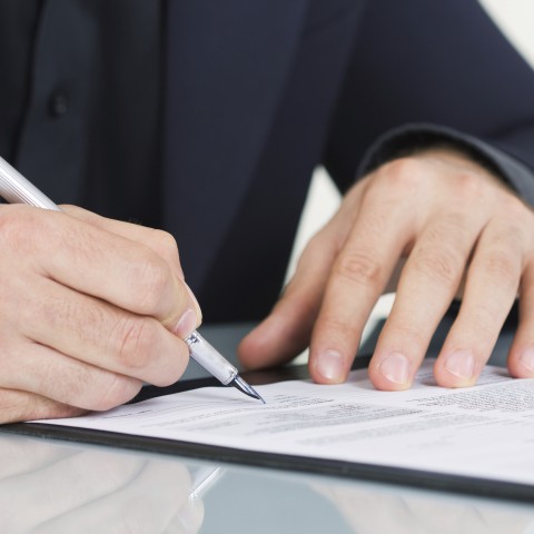 Person signing a rental agreement with a pen