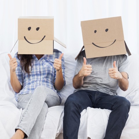 Two People with Smiley Cardboard Boxes on Their Heads Giving the Thumbs-up Sign