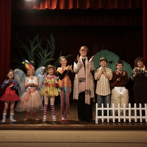 Children in Costumes on a Stage with an Adult