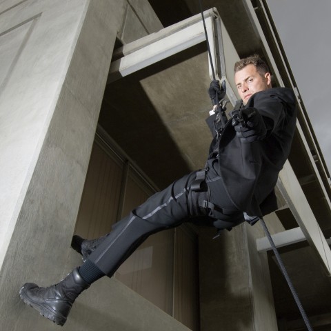 Man Scaling Building and Pointing to Camera