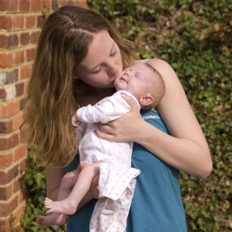 A Mother Holding and Kissing Her Baby on the Cheek