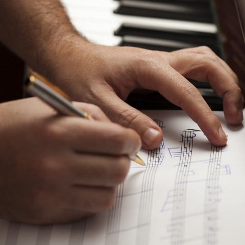 A Close-up of Hands and a Musical Composition in Progress.