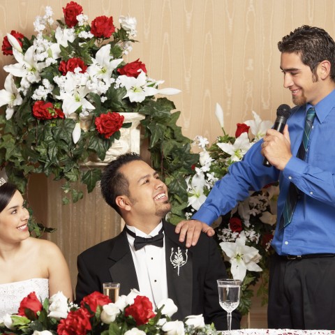 Married Couple During Reception, Sitting at Their Table While a Young Man Gives a Wedding Speech