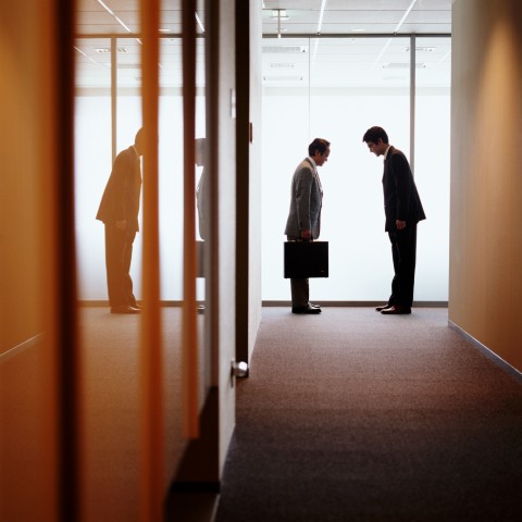 Two Japanese Businessmen Bowing To Each Other in a Hallway