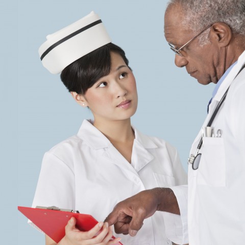 A Doctor Pointing to Something on a Clipboard a Nurse Is Holding