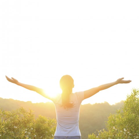 Young Woman Standing Outside with Outstretched Arms in the Sun